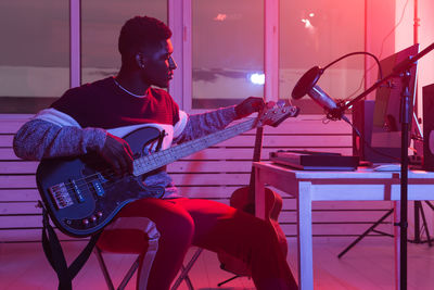 Rear view of man playing guitar on stage