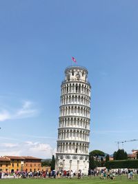 Group of people in front of leaning tower against sky