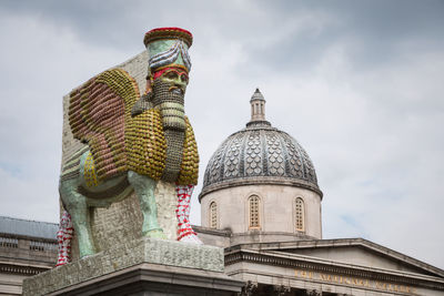 Low angle view of statue and building against sky