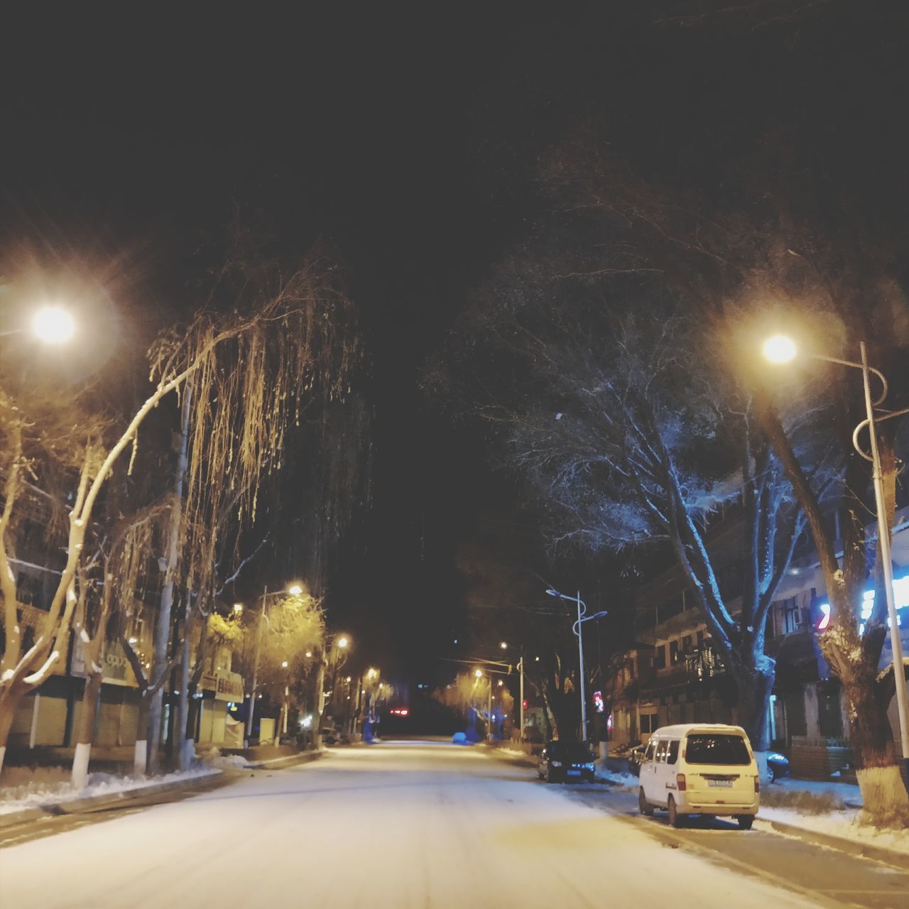 ILLUMINATED STREET LIGHTS ON ROAD AT NIGHT