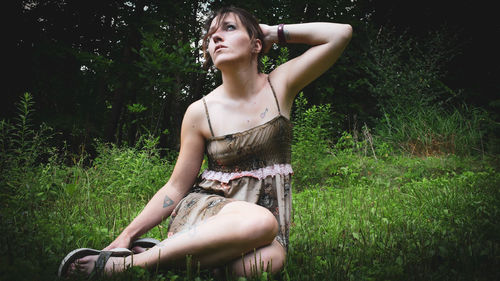 Beautiful young woman sitting on field