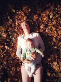 High angle view of mother and newborn lying on fallen autumn leaves