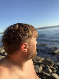 Bearded man pondering the beautiful lake on a sunny day.