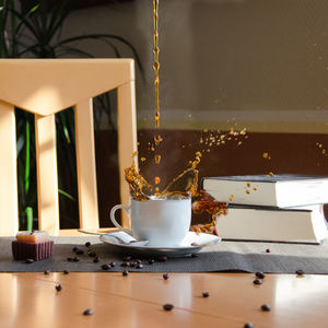Coffee pouring in cup by books on table
