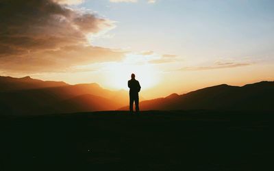 Silhouette man standing on mountain against sky during sunset