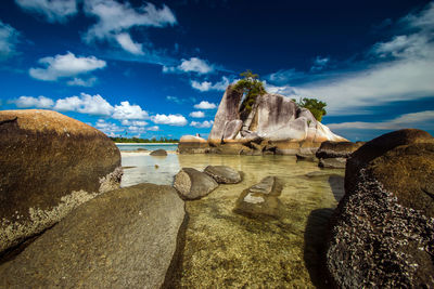 Rock formations on shore against sky