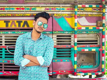 Portrait of young man standing against multi colored truck