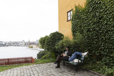 Female friends talking to each other on bench near plants at park