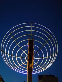 Low angle view of illuminated ferris wheel against blue sky