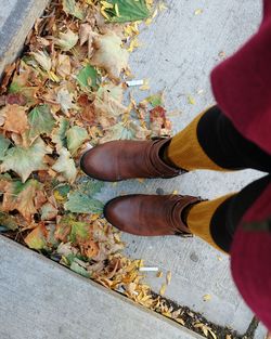 Low section of woman standing by autumn leaves