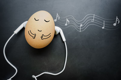 Close-up of anthropomorphic face on egg amidst in-ear headphones