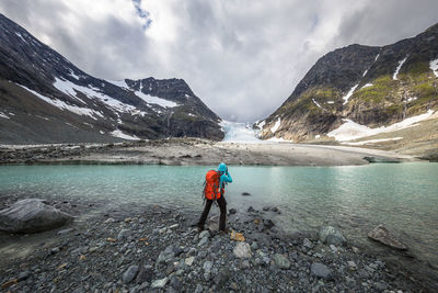 Rear view of person standing at lakeshore during winter