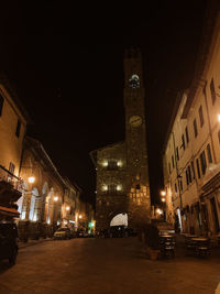 Illuminated street amidst buildings in city at night