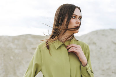 Fashion beauty portrait of young woman with long hair in green organic shirt on desert background