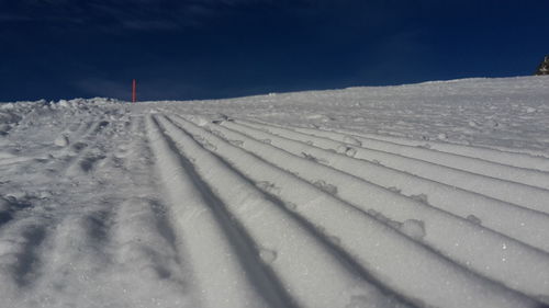 Tire tracks on snow landscape against sky