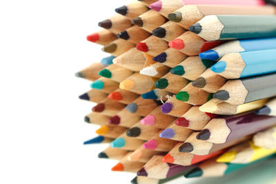 Close-up of colored pencils on table against white background