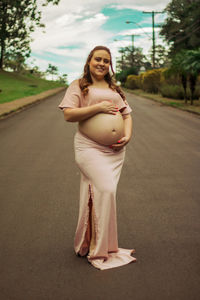 Portrait of a smiling young woman standing on road