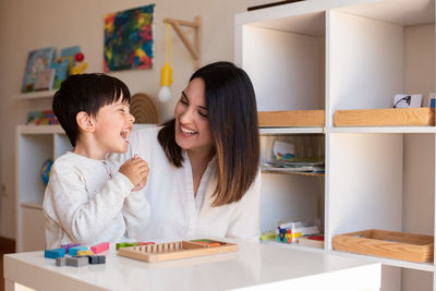 Mother assisting son in puzzle sitting at home