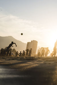 People at beach against sky during sunset