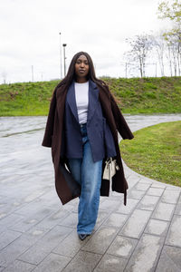 Portrait of young woman standing on footpath