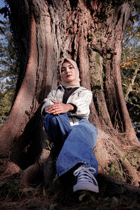 Portrait of boy sitting on tree trunk