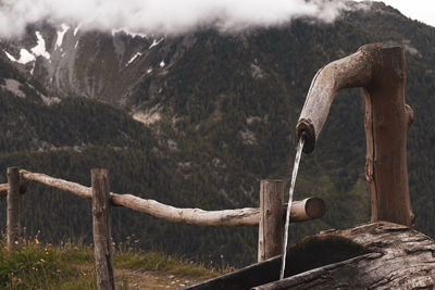 Close-up of metal fence on landscape against mountains