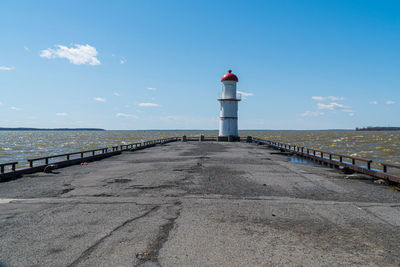 Lighthouse on pier by sea against sky