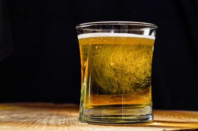 Close-up of beer in glass on table against black background