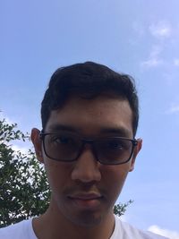 Portrait of young man wearing eyeglasses against sky