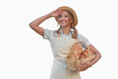 Portrait of smiling woman holding hat against white background