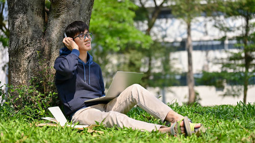 Young woman using laptop while sitting on field