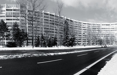 Road by buildings in city against sky