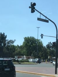 Road sign by street against sky