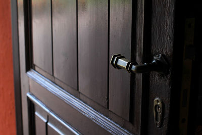 Detail of wooden door, brass handle and lock in the foreground.