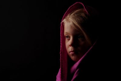 Close-up of girl against black background