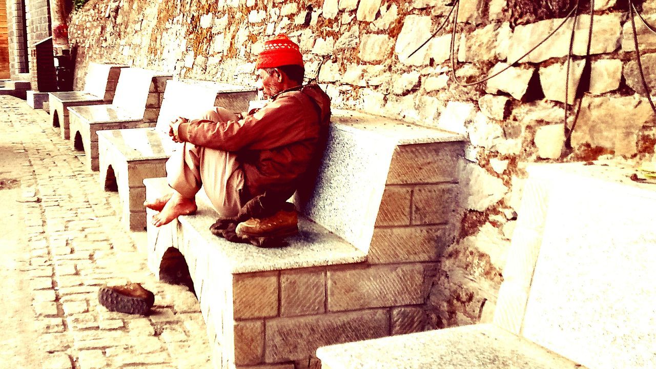 MAN SITTING WITH CROSS IN THE BACKGROUND