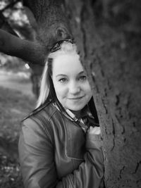 Portrait of smiling woman against tree trunk