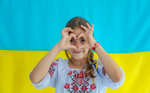 Smiling girl gesturing against ukrainian flag