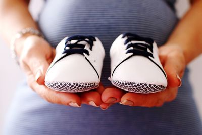 Low section of pregnant woman holding baby booties