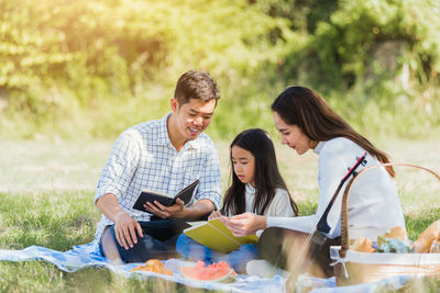 Cheerful family reading book during picnic