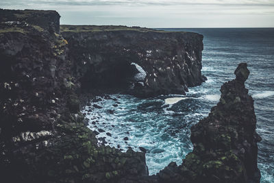 Rock formations by sea against sky