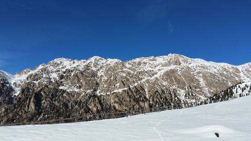 Scenic view of snow covered mountains against clear sky