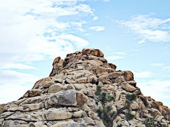 Low angle view of rocks against cloudy sky