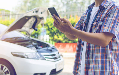 Midsection of man using mobile phone in car