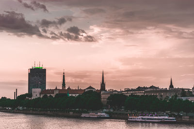 View of buildings at waterfront against cloudy sky