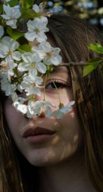 Close-up portrait of teenage girl by white flowers