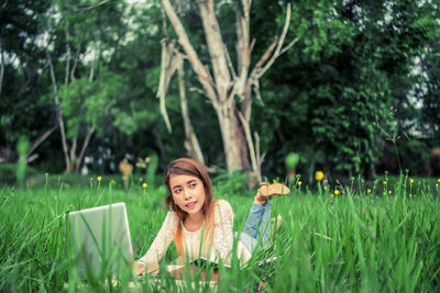 Young woman using laptop on field