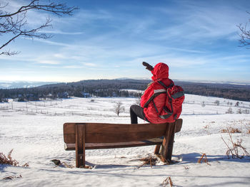 Side view of man walking in snow on winter day, mountain landscape. hiker in red with red backpack.