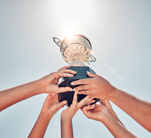Cropped hands of woman holding trophy against white background