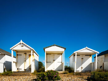 Low angle view of beach huts against clear blue sky